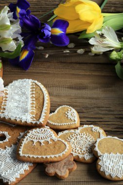  Sarı kurdeleli kalp şeklinde makro zencefilli kurabiye, ahşap arka planda çiçekler.
