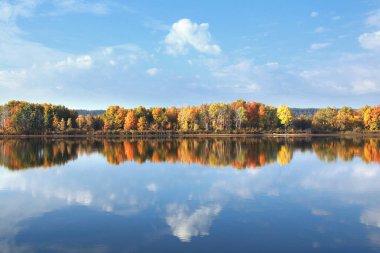 Renkli ağaçların sonbahar manzarası sakin nehrin yansıyan yüzeyine yansıyor.