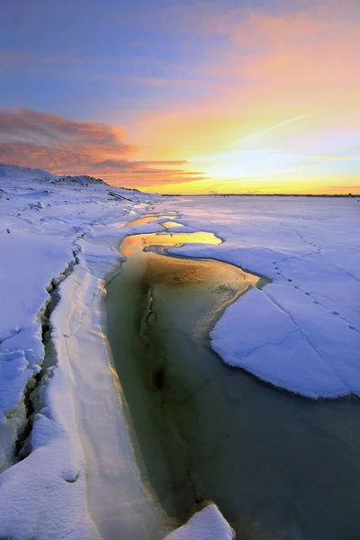 冬日的风景夕阳西下在冰封的河上 城市在地平线上 — 图库照片