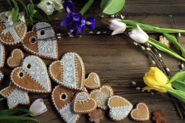  Sarı kurdeleli kalp şeklinde makro zencefilli kurabiye, ahşap arka planda çiçekler.