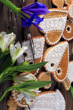  Sarı kurdeleli kalp şeklinde makro zencefilli kurabiye, ahşap arka planda çiçekler.