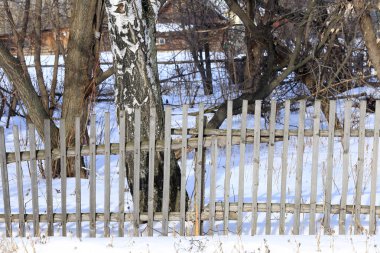 Kışın beyaz kar üzerinde ıssız bir köy çiti.