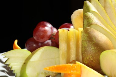 Siyah arka plan stüdyosunda beyaz tabakta güzel bir meyve salatası.