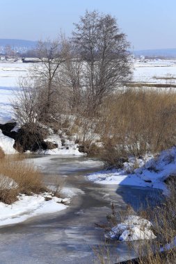 Baharın başlarında, ormanın yakınındaki donmuş nehir manzarası.