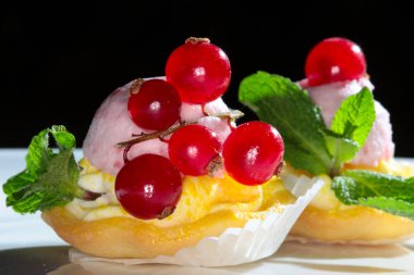 Koyu bir arka plan stüdyosunda kırmızı frenk üzümlü nefis bir pasta.