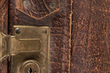 Eski model deri valizin üzerindeki kilit ve bağlayıcıların yakın plan parçaları kahverengi.