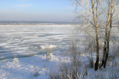 Buz deposunun altındaki manzaralı kış manzarası. Muhteşem mavi gökyüzü sisi ve kıyı şeridindeki ağaçlarda don.