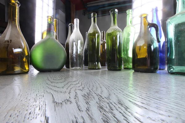 スタジオの灰色の木製の床の上にあるカラフルなほこりの多いボトル — ストック写真