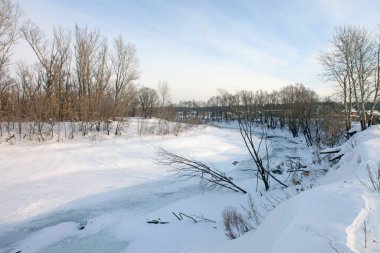 Kış manzarası nehirde gün doğumu ve bulutlu bir sabahta çıplak ağaçlar.