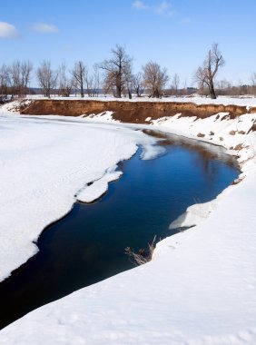 İlkbaharın başlarında harika bir manzara nehirde ve güneşli bir günde mavi gökyüzünde beyaz bulutlar