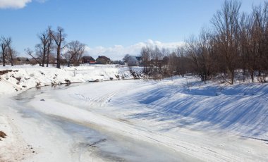 İlkbaharın başlarında harika bir manzara nehirde ve güneşli bir günde mavi gökyüzünde beyaz bulutlar
