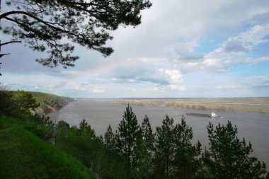 Pahalı bahar manzarası Kama Nehri, gökkuşağı ve yüzen mavna, güneşli bir günde ormanlar ve çayırlar, tepeden manzara