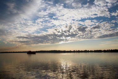 güzel yaz manzarası güzel gün batımı nehir üzerinde, güzel bulutlar ve ağaçlar kıyıda.