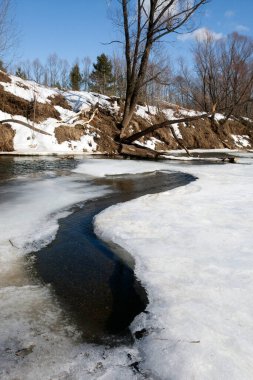İlkbaharın başlarında harika bir manzara nehirde ve güneşli bir günde mavi gökyüzünde beyaz bulutlar