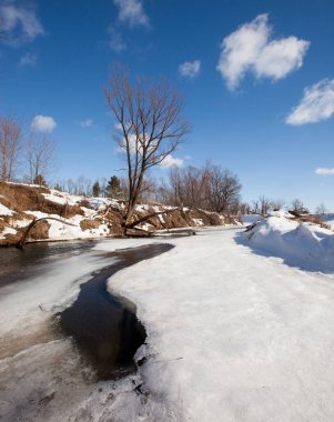 İlkbaharın başlarında harika bir manzara nehirde ve güneşli bir günde mavi gökyüzünde beyaz bulutlar