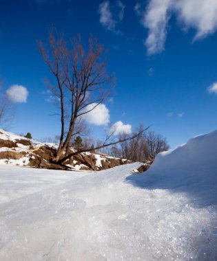 İlkbaharın başlarında harika bir manzara nehirde ve güneşli bir günde mavi gökyüzünde beyaz bulutlar