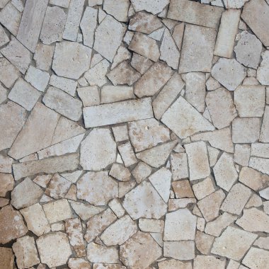 Doğal taştan duvarın yakın çekim bölümü güneş ışığıyla kaplı.