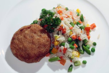 Beyaz tabakta sebze garnitürlü kızarmış pirzola.