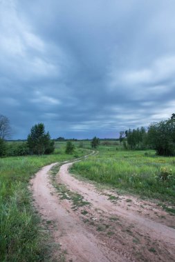 Yaz manzarası yolu gün batımı mavi gökyüzünde dramatik bulutlar ve yeşil çayırlar