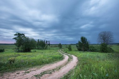 Yaz manzarası yolu gün batımı mavi gökyüzünde dramatik bulutlar ve yeşil çayırlar