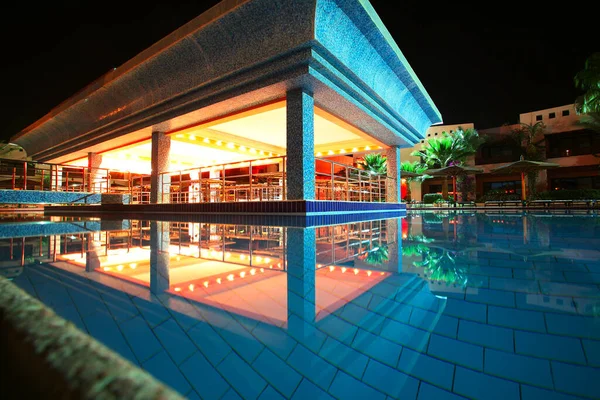 seaside resort hotel building and landscaped grounds with pool in summer night