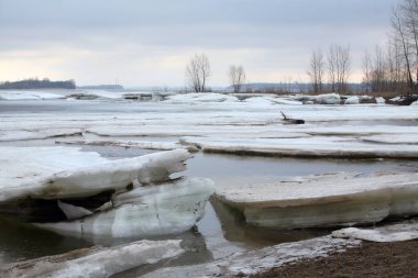 Baharın başlarında bulutlu bir günde nehir üzerindeki buz tabakası sürükleniyor.