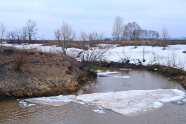 Baharın başlarında bulutlu bir günde nehir üzerindeki buz tabakası sürükleniyor.