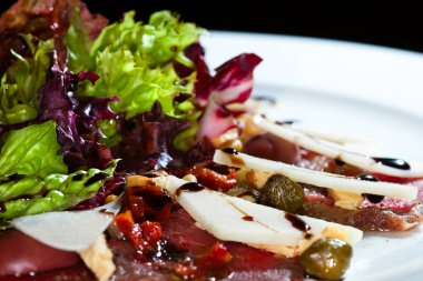 Yakın plan güzel iştah açıcı salata. Beyaz tabakta, karanlık stüdyo arka planında. 