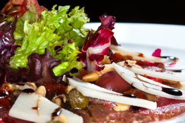 Yakın plan güzel iştah açıcı salata. Beyaz tabakta, karanlık stüdyo arka planında. 