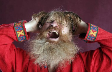 Kırmızı gömlek stüdyosunda uzun sakallı, bıyıklı ve ıslak sarı saçlı kutsanmış birinin yakın plan portresi.