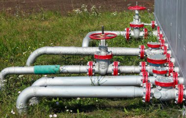 Yazın çimlerin arka planında bir tarladaki boru ve vanaların yakın plan çekimi.