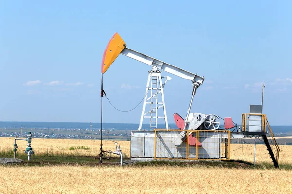 summer landscape oil pumps in the grain fields on the background of the blue sky on a sunny day