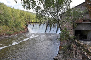 Nehirdeki eski barajın yaz manzarası güneşli bir günde dağların ve ormanların arka planında 