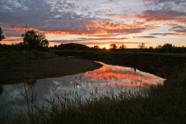 Gün batımında, ormanın ve nehrin yakınındaki manzara bulutlu.