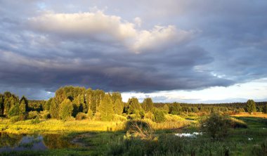Gün batımında, ormanın ve nehrin yakınındaki manzara bulutlu.