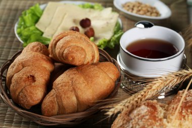 Hamur işleri, meyveler, peynirler, fındıklar, buğdaylar ve marullar masada.