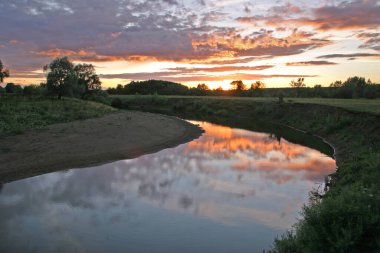 Gün batımında, ormanın ve nehrin yakınındaki manzara bulutlu.