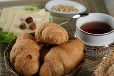 Hamur işleri, meyveler, peynirler, fındıklar, buğdaylar ve marullar masada.