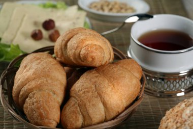 Hamur işleri, meyveler, peynirler, fındıklar, buğdaylar ve marullar masada.