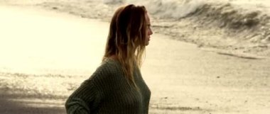 Siyah kumsalda sıcak gün doğumu. Seksi genç bir kız. Mayo ve bluzla çok seksi ve duyarlı pozlar veriyor.