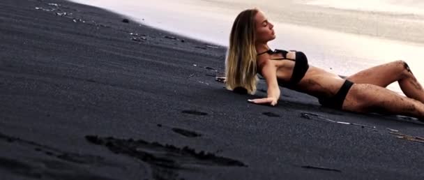 Young Tanned Skin Girl Trying Lay Deep Black Sand Beach — Stock Video