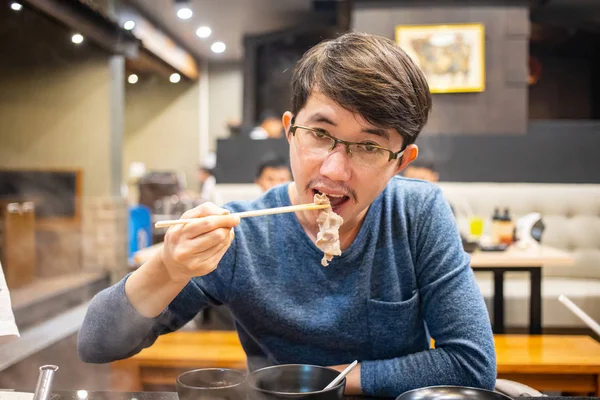 Japon Shabu restoranında bir parça haşlanmış domuz yiyen bir adam.