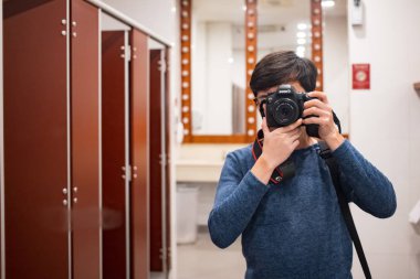 Bangkok, Tayland, Sep 7, 2019 - DSR kamera kullanan bir adam tuvaletteki aynada kendine yansıma fotoğrafı çekiyor