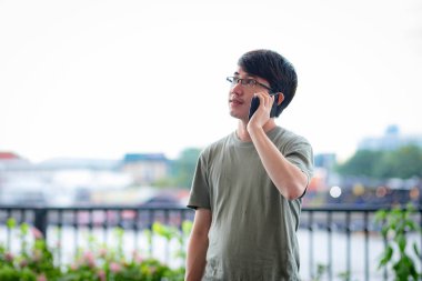 Nehir manzaralı telefondan arayan adam.
