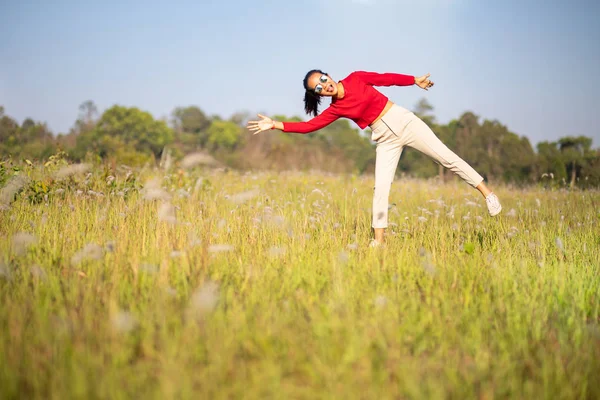 Hipster Asian woman in red and sunglasses on white flower and grass field