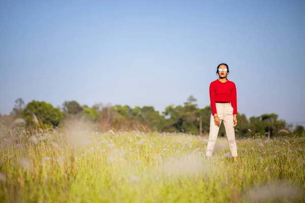 Hipster Asian woman in red and sunglasses on white flower and grass field