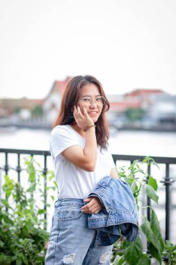 Beyaz tişörtlü, yırtık kotlu Asyalı inek kadın.