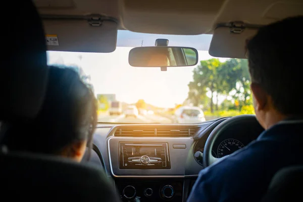 Rear view of couple inside car driving on road, Point of view of driver inside car