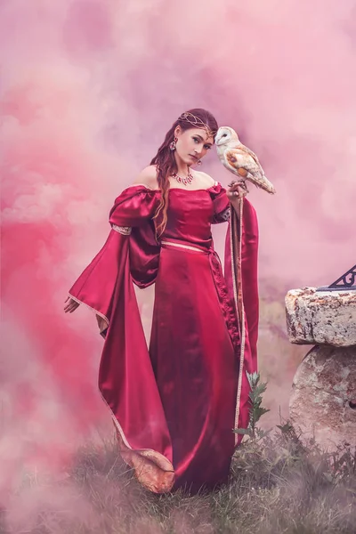 Kırmızı duman dans güzel kadın uzun kırmızı elbiseli, büyücü, elini üzerinde uçan bir kuşu ile