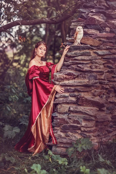 Güzel ortaçağ kadın, büyücü, elini üzerinde uçan bir kuşu ile. İnanılmaz sahne yakınındaki antik ark.